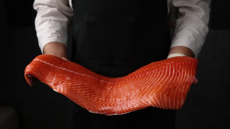 The chef holds a salmon fillet in his hands