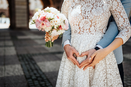 Bride and groom's hands, holding a wedding bouquet.