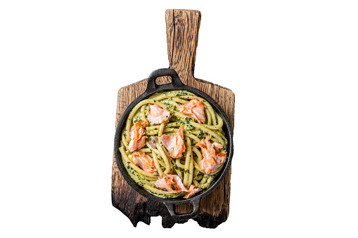 Salmon Bucatini pasta with creamy spinach sauce and fish fillet.  Isolated on white background, top view