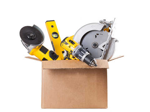 cardboard box with tools (grinder, circular saw, drill, leveler) on white background