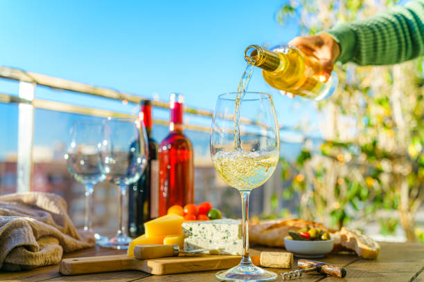 istock Hand pouring white wine from bottle into a glass in a terrace 1914836916