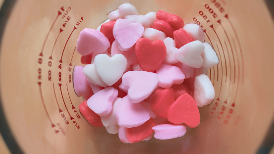 Heart shape desserts made from flour in clear glass measuring cup, pastel, representing love and romance. Lovely valentine sweet backdrop. Top View, generative ai