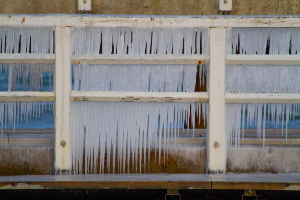 Icicles hanging from a wooden railing on a cold day.