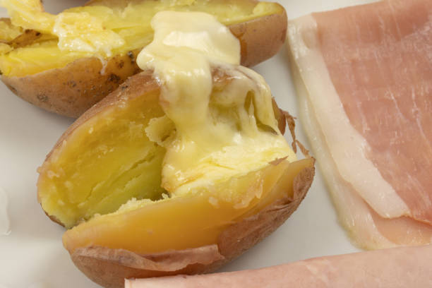 Melted raclette cheese on top of boiled potatoes, served with pickled onions and cucumbers a Swiss specialty, the Zurich Christmas Market, Switzerland