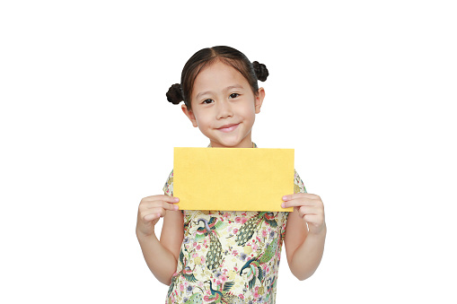 Happy Chinese New Year. Asian little girl wearing cheongsam smiling and holding gold envelope isolated on white background.