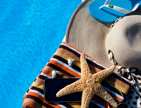 Starfish, headphones, sun spray, women's hat and flip flops on the background of the pool concept of relaxation. Summer family vacation concept