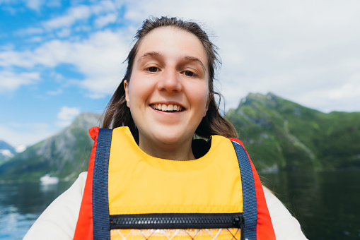 Smiling female making selfie of herself while kayaking at scenic sea with summer mountain new in West Norway, Scandinavia