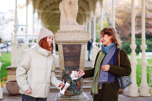 two girls drink water from the Snake Spring mineral water in resort town Karlovy Vary