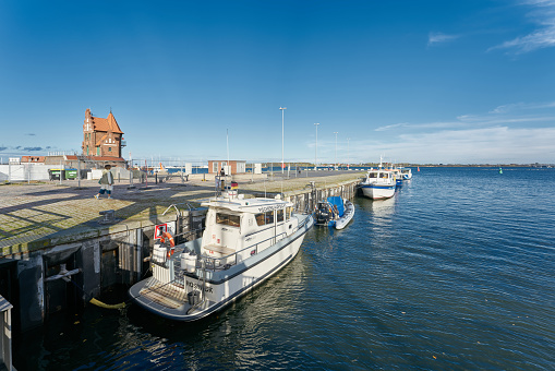 Stralsund, Germany – October 29, 2023: Boat of the fishing inspectorate in the port of Stralsund in Germany. The historic pilot house, lotsenhaus, in the background