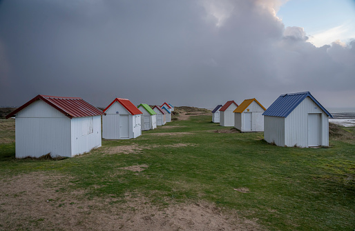 View of colorful bathing wooden cabins of Gouville on the dunes