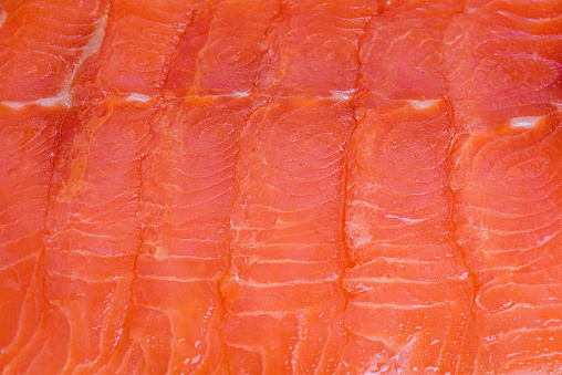 Red fish macro photo as background. Lightly salted salmon fillet cut into thin pieces.