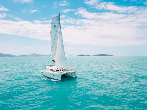 Catamaran Sails through calm turquoise water near the Whitsundays