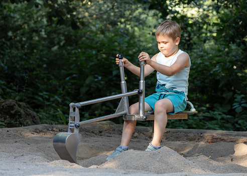 The little digger is working on the playground with a serious facial expression.
