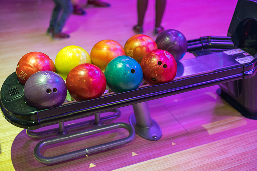 Close-up view of dispenser with bowling balls of various weight categories is showcased.