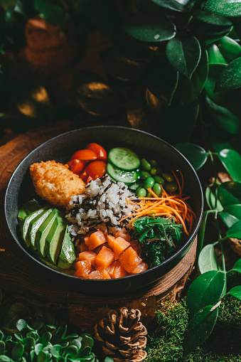 Healthy vegetarian dinner. Lunch poke bowl full of vegetables, trout slices, seafood. Assortment of Hawaiian food. Exotic cuisine concept.