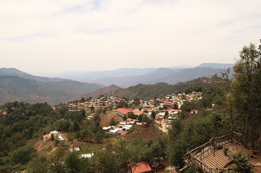 View from a view point/mirador onto San Jose del Pacifico, a small village in Oaxaca, surrounded by a dense forest and hills, Oaxaca, Mexico 2022