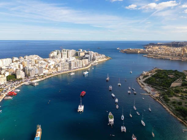 Discover Sliema and Valletta in Malta overlooking the Mediterranean Sea with boats sailing on the blue ocean Surface. Seen a sunny day.
