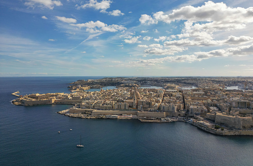 A sunlit picture overlooking Malta's historic medieval city of Valletta, surrounded by the Mediterranean Sea on a sunny day.