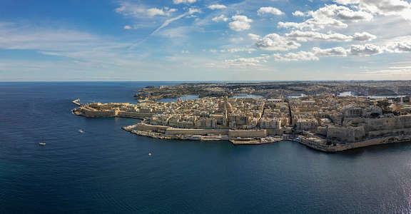 A sunlit picture overlooking Malta's historic medieval city of Valletta, surrounded by the Mediterranean Sea on a sunny day.