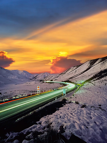 Enchanting allure of Lindis Pass at sunset. Capturing the magic of long exposure, witness mesmerizing light trails along the scenic highway in South Island, New Zealand. A journey through time.
