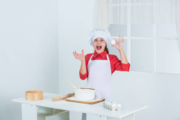 istock girl is adding an egg to the dough, chef 1915289214