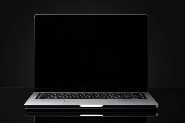 Open laptop with black screen against black background