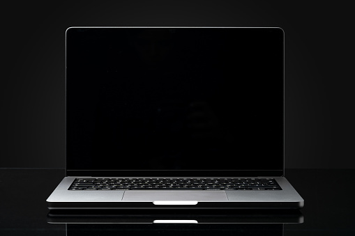 Open laptop with black screen against black background copy space