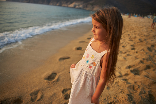 Little girl enjoying a tropical paradise beach during sunset.