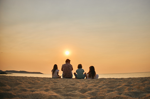 A family enjoying a tropical paradise beach during sunset.