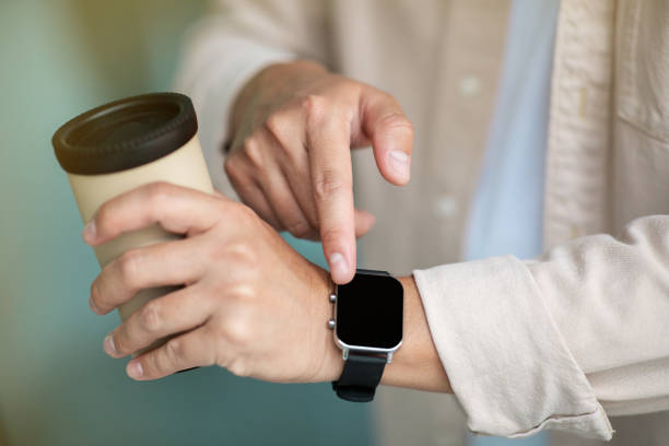 istock Man with cup of coffee checking time on smart watch 1915346278