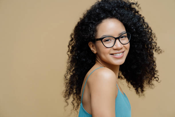 Radiant woman in glasses, teal tank top, beige background