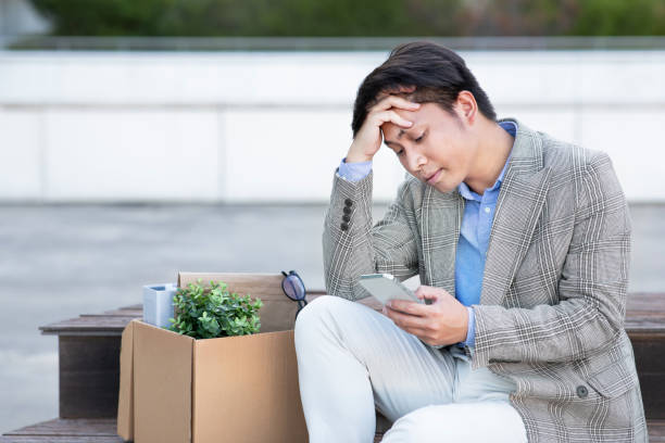 istock Fired japanese office worker guy holds phone in urban area 1915363780
