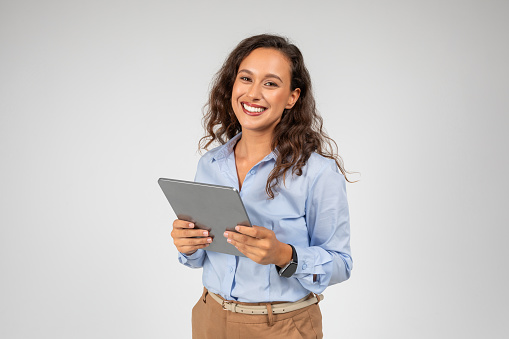 Smiling caucasian young businesswoman use tablet, app for social networks, presentation business, isolated on gray studio background. Work and chat on gadget, study online with technology