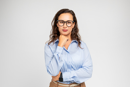 Calm pensive millennial caucasian business woman in formal wear, glasses think, isolated on gray background studio background. Question, solution, choice at work, ad and offer