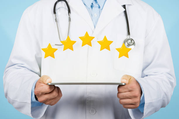 istock Doctor man holding tablet displaying five-star rating, blue background 1915422152