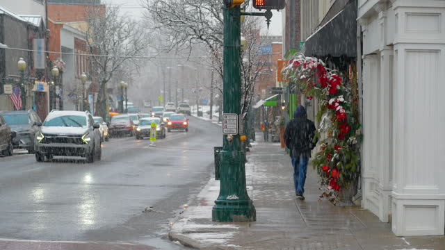 Man Walks Down Main Street of Small Town at Christmas