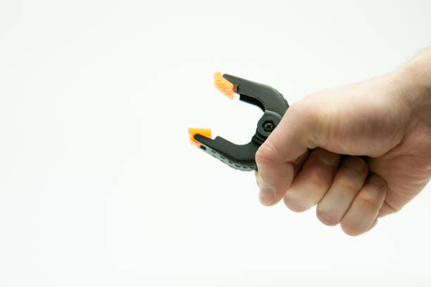 istock Male hand holding plastic string clamp tool isolated on white background 1915435973
