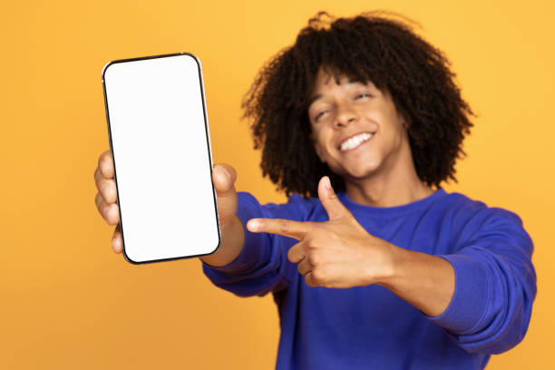istock Positive Black Guy Holding Smartphone And Pointing At Blank White Screen 1915482012
