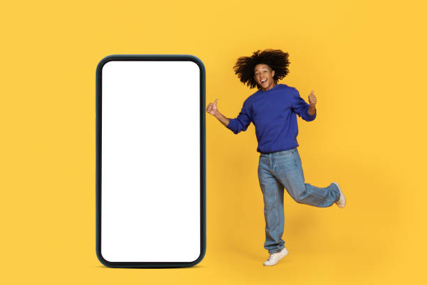 istock Great Offer. Black Man Jumping Near Blank Smartphone And Gesturing Thumbs Up 1915482018