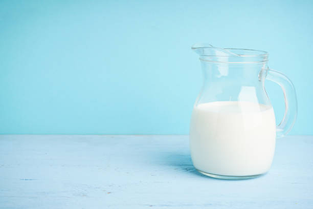 istock Jug with milk on a wooden light blue background, space for text. 1915483062