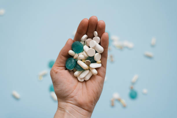 istock Various medicinal pills and capsules on a woman's palm on a blue background 1915525328