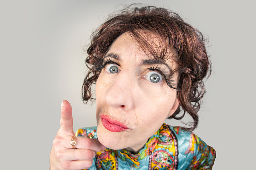 A funny fisheye image of a middle aged woman in a vintage paisley robe and 1960s hair fashion pointing her finger, scolding.