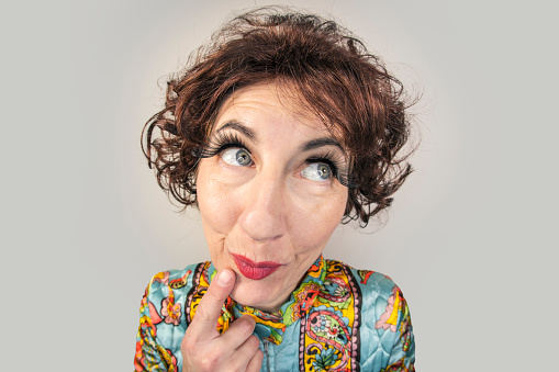 A funny fisheye image of a middle aged woman in a vintage paisley robe and 1960s hair fashion pondering something.