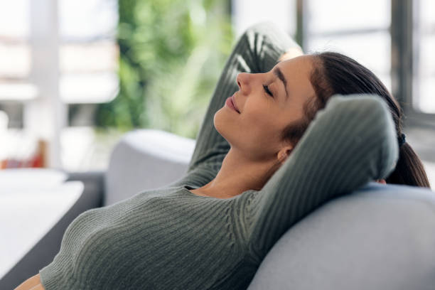 istock Pensative young woman working with her laptop while looking forwards sitting on a couch at home. 1915554366