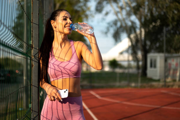 istock Happy female athlete drinking fresh water from the bottle and making rest from working out outdoor in the city park court 1915569362