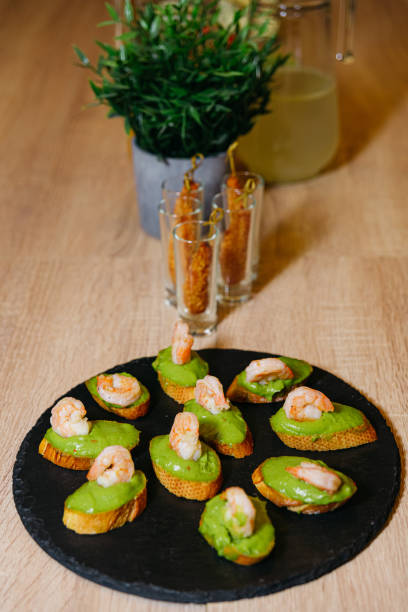istock Multiple portions of crostini featuring guacamole sauce and crispy shrimp, elegantly served on a black slate board 1915577611