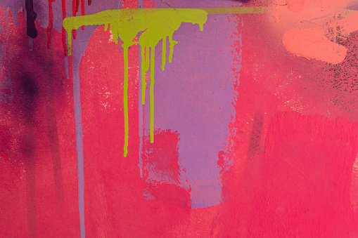 Messy paint strokes and smudges on an old painted wall. Pink, purple, yellow, blue color drips, flows, streaks of paint and paint sprays.