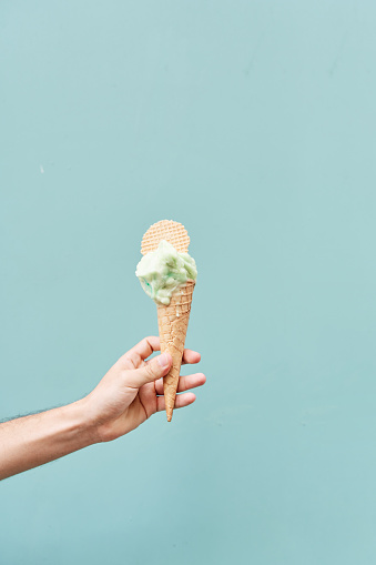Ice cream cone on a blue background. man holding the ice cream by hand.