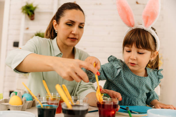istock Mother and child having fun painting and decorating Easter eggs in the kitchen 1915634150