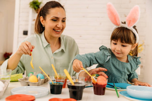 istock Mother and child having fun painting and decorating Easter eggs in the kitchen 1915634157